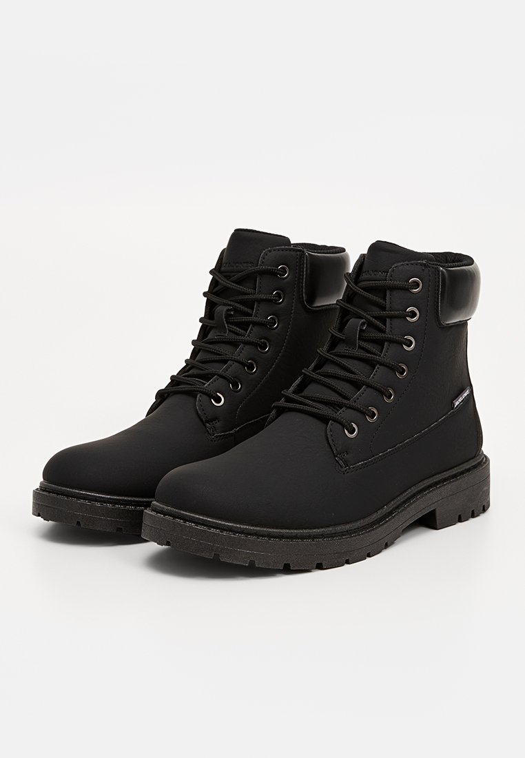 Bottines noires en matériau synthétique texturé. Comprend un bout arrondi, un laçage, un col rembourré et une semelle en caoutchouc épaisse.