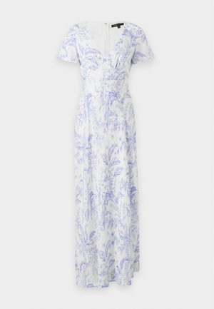 Femme portant une robe maxi fleurie blanche et bleu clair à manches courtes, des chaussures blanches à talons, et tenant un sac à main en cuir marron.