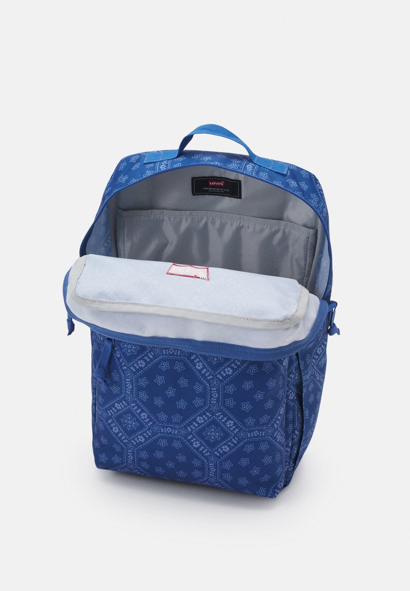 Sac à dos bleu en tissu avec un motif géométrique. Intérieur gris clair avec une poche à rabat et une étiquette Levi's visible.