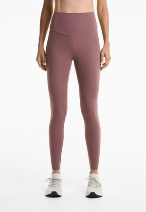 Hoge taille legging in gedempt mauve, gemaakt van rekbare stof. Glad, aansluitend ontwerp, naadloze tailleband en een lichte glans op het oppervlak.