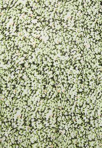 Kangasta tekstuuriga elav roheline ja must muster väikeste roosa aktsentidega, millel on voldid, mis lisavad mõõtmeid.