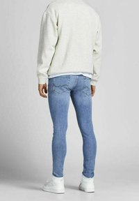 Light blue skinny jeans with a faded pattern, contrasting stitching, and two back pockets, paired with a light gray sweatshirt.