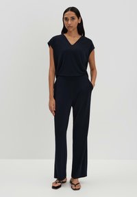 Navy jumpsuit met korte mouwen, V-hals, elastische tailleband en rechte pijpen. Gemaakt van zachte stof, met zijzakken.