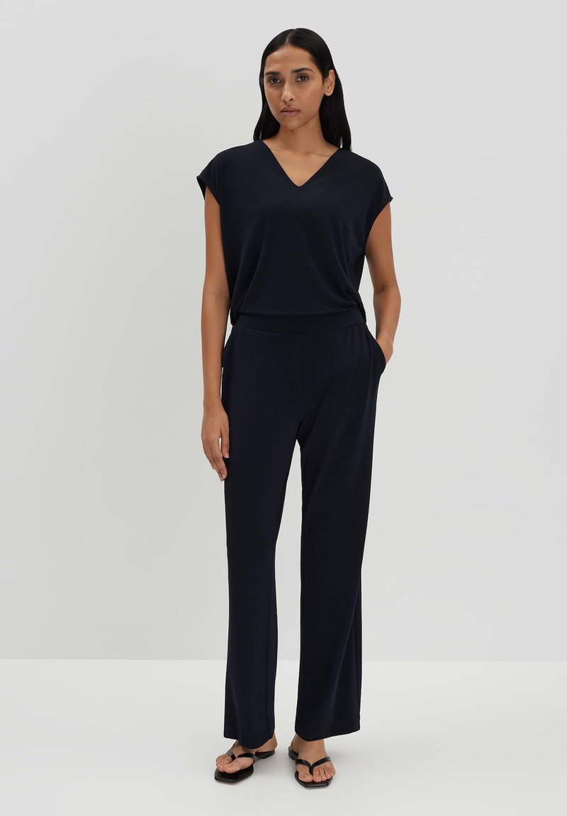 Navy jumpsuit met korte mouwen, V-hals, elastische tailleband en rechte pijpen. Gemaakt van zachte stof, met zijzakken.