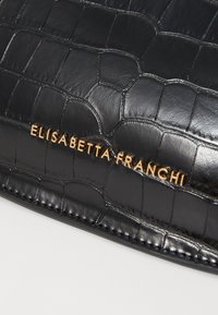 Black crocodile-embossed leather surface with gold "Elisabetta Franchi" logo lettering on a bag or accessory.