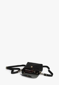 Schwarze Leder-Umhängetasche mit Klappverschluss, goldfarbenen Beschlägen und verstellbarem Riemen. Innenraum mit mehreren Taschen zur Organisation.