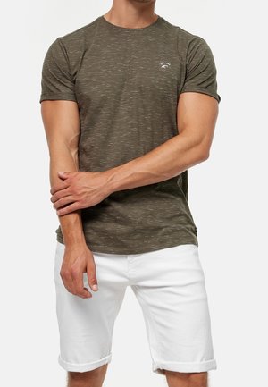 Zielony oliwkowy t-shirt z krótkim rękawem o teksturowanym wykończeniu, okrągły dekolt i mały detal z logo. Połączony z białymi szortami z denimu.