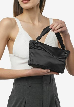 Borsa in satin nera con una tracolla intrecciata, caratterizzata da una superficie testurizzata e una forma simile a un sacchetto, tenuta in mano da una persona.
