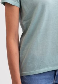 Světle zelené tričko s krátkým rukávem vyrobené z jemné bavlny, s uvolněným střihem a kulatým výstřihem s hladkým povrchem.