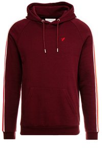 Sudadera con capucha burdeos, con bolsillo frontal, cordones, rayas rojas y blancas en las mangas, y pequeño logo de un pájaro rojo en el pecho.