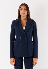 Blazer doppiopetto blu navy con grandi bottoni, vestibilità su misura, rever a scalfo e tasche laterali. Tessuto liscio, design strutturato.