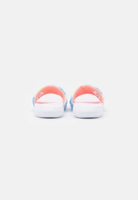 Sandales ouvertes à l'arrière avec un dessus bleu clair et vert, texture douce, et semelles en caoutchouc blanches. Accentuées par un intérieur rose vif.