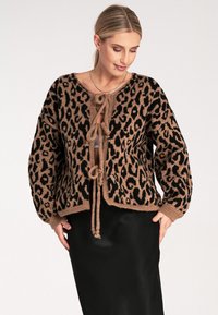 Leopardenmuster Strickjacke in Schwarz und Beige mit Krawattenverschluss. Hat einen lockeren Schnitt und lange Ärmel. Weicher Stoff und gerippter Saum.