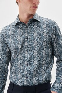 Langärmliges Hemd mit Knopfleiste in dunklem Teal mit weißen Paisley- und Blumenmustern, ausgestattet mit einem klassischen Kragen und dunklen Knöpfen.