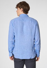 Camicia a maniche lunghe azzurro chiaro in tessuto intrecciato e testurizzato. Presenta un colletto e polsini con bottoni, con hemline curvo.