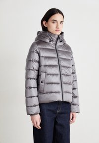 Doudoune grise avec capuche, design matelassé, fermeture éclair et poches latérales. Fabriquée en matériau brillant et lisse avec un léger éclat.