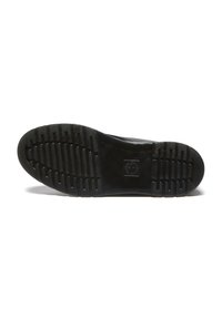Suela de zapato negra con profundas ranuras horizontales y un logotipo cuadrado central, fotografiada sobre un fondo blanco.