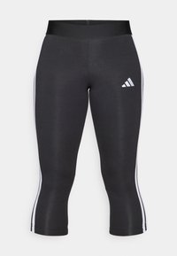 Juodos capri kelnės su plačiu juosmeniu, turinčios baltas šonines juosteles ir baltą „Adidas“ logotipą kairiajame šlaunyje. Lygus paviršius.