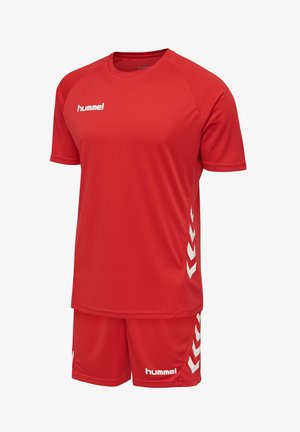 Rødt sportssæt med kortærmet skjorte og shorts med hvide hummel-logoer og chevron-mønstre på siderne, lavet af åndbart stof.