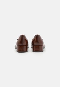 Brown patent leather shoes with a low block heel and a sleek, pointed toe design. Smooth texture with minimal hardware accents.