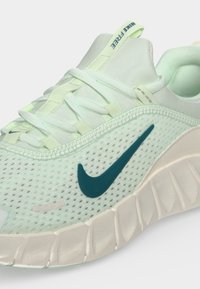 Ανοιχτό πράσινο αθλητικό παπούτσι Nike για τρέξιμο με διχτυωτό επάνω μέρος, σκούρο πράσινο λογότυπο Swoosh και παχιά μπεζ σόλα με υφασμένα αυλάκια.