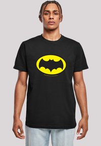 Sort bomulds T-shirt med en stor gul oval og et sort Batman-logo i midten. Kortærmet, design med rund hals.