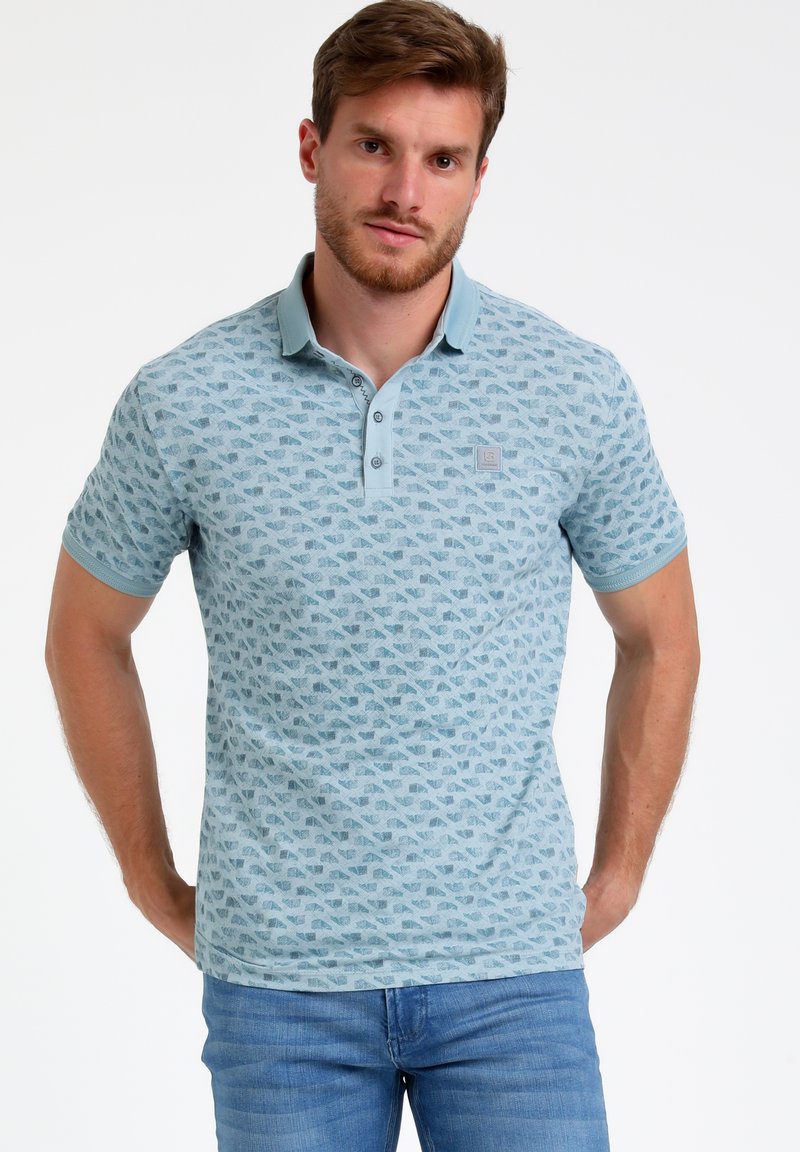 Camisa polo azul claro con un diseño estampado y un cuello en contraste. Tiene tres botones y mangas cortas. Tejido de textura suave.