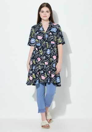 Kurzärmlige, marineblaue Tunika mit floralem Muster in Pink und Blau; gestuftem Saum. Kombiniert mit hellblauen Leggings mit Spitzenbesatz.