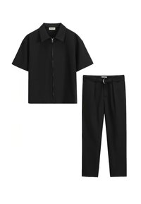 Chemise noire à manches courtes avec fermeture éclair associée à un pantalon noir cintré comportant une boucle de ceinture avec un détail en anneau métallique. Texture de tissu lisse.