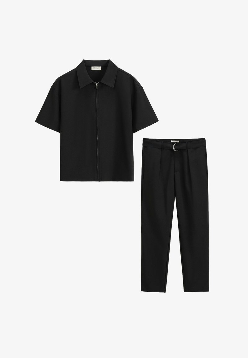 Chemise noire à manches courtes avec fermeture éclair associée à un pantalon noir cintré comportant une boucle de ceinture avec un détail en anneau métallique. Texture de tissu lisse.