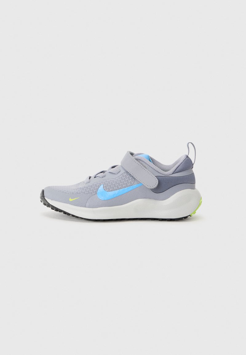 Chaussure de sport gris clair avec accents bleus et logo jaune, dotée d'une tige en mesh, d'un collier rembourré, d'une sangle réglable et d'une semelle texturée noire.