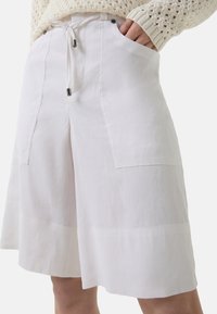 Witte linnen shorts met een ontspannen pasvorm, voorzien van frontzakken, een trekkoord in de taille en zichtbare stiksels aan de rand. Gladde textuur.