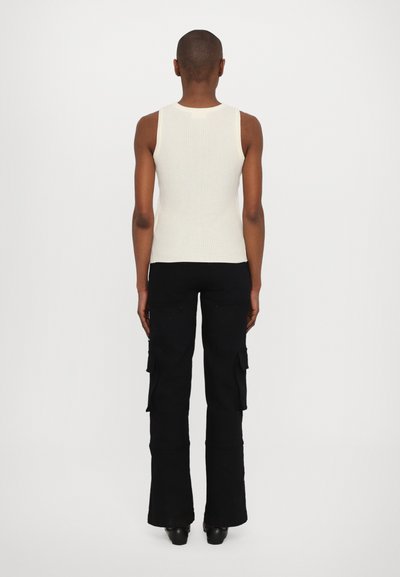 Débardeur blanc à côtes et pantalon cargo noir avec des jambes évasées. Les pantalons cargo disposent de poches latérales et d'un tissu texturé, vus de l'arrière.