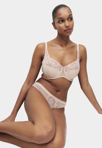 Lyserød blonde-bh og matchende trusse. Bh'en har blomsterblonde og prikket mesh, mens trussen har blondekant og prikmønster.