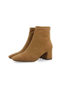 Bottines en suède beige avec un bout pointu et un talon bloc. Présentent des coutures décoratives et un petit accent métallique à l'arrière.