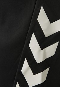 Svart tyg med djärva vita chevronmönster i en kontrasterande design, som betonar textur och geometriska former.