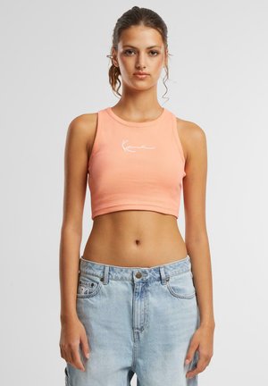 Rosa ribbestrikket crop topp med rund hals og hvitt brodert logo. Kombinert med lyseblå denimbukser med knappelukk.
