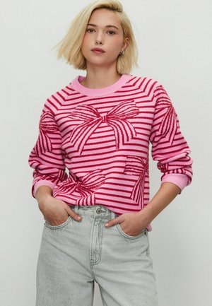 Lyserød stribet trøje med store røde sløjfemønstre, rund hals og ribbede manchetter. Sammen med lys grå jeans.