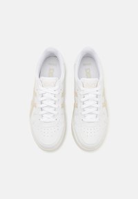 Vita sneakers med en mjuk läderöverdel, perforerad tå, snörning och subtila beige accenter på sidorna. Klassisk låg design.