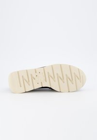 Schuhsohle mit einem Zickzackprofil, ausgestattet mit einem schwarzen Stoffoberteil und einer cremefarbenen Gummisohle, die Grip und Unterstützung bietet.