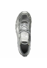 Silberner Sportschuh mit einer glatten, reflektierenden Oberfläche, abgerundeter Zehenpartie, Schnürverschluss, gepolstertem Schaft und Logo-Akzenten auf der Zunge.