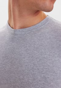 Grå crew-neck t-shirt lavet af blødt, tekstureret stof; har en glat halsudskæring og minimale syninger, hvilket fremhæver dets afslappede design.