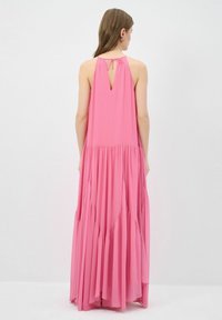 Vestido maxi rosa en una tela ligera, con espalda con abertura en forma de llave y diseño en capas con secciones fluidas y recogidas para añadir textura.