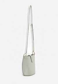 Sac seau gris clair avec une texture lisse, doté d'une longue sangle réglable, d'accents en métal doré et de coutures noires contrastantes.