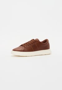 Braune Ledersneaker mit glatter Textur, runder Zehenform, flachen Schnürsenkeln und einer cremefarbenen Gummisohle mit strukturiertem Profil.