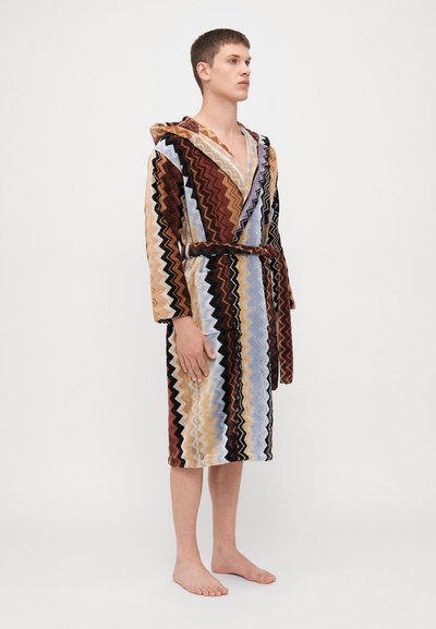 Rochie de baie cu glugă, având un model în zigzag în nuanțe de brun, crem, albastru și negru. Fabricată dintr-un material texturat, cu talie legată.