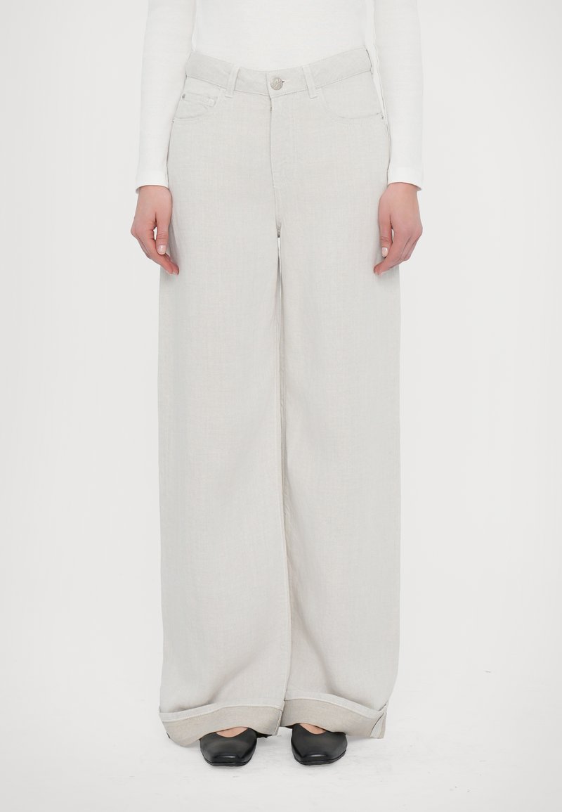 Wide-leg, light gray trousers made of lightweight fabric with a smooth texture; features a button closure and rolled cuffs, paired with black shoes.
