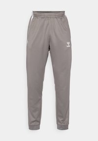 Grijze sportbroek met een elastische tailleband, taps toelopende benen en witte accenten aan de zijkant. Bevat een klein merkje op de bovenbeen. Glad textuur.