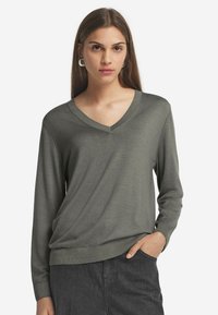 Grauer V-Ausschnitt-Pullover mit langen Ärmeln, hergestellt aus weichem Stoff. Hat eine lockere Passform und gerippte Bündchen sowie einen gerippten Saum für zusätzliche Textur.