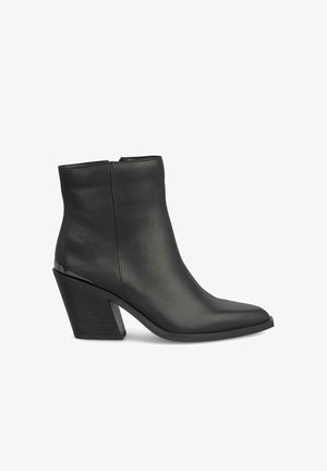 Botín de cuero negro con punta afilada, tacón cuadrado angular, textura suave y diseño minimalista. Cuenta con una cremallera en la parte trasera.